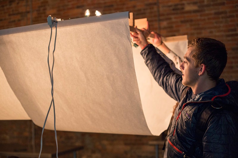 Zach Meyer holds up one end of a prototype lighting installation