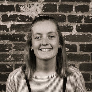 Photograph of a smiling first-year SPD student, Molly Older, in front of a brick wall.