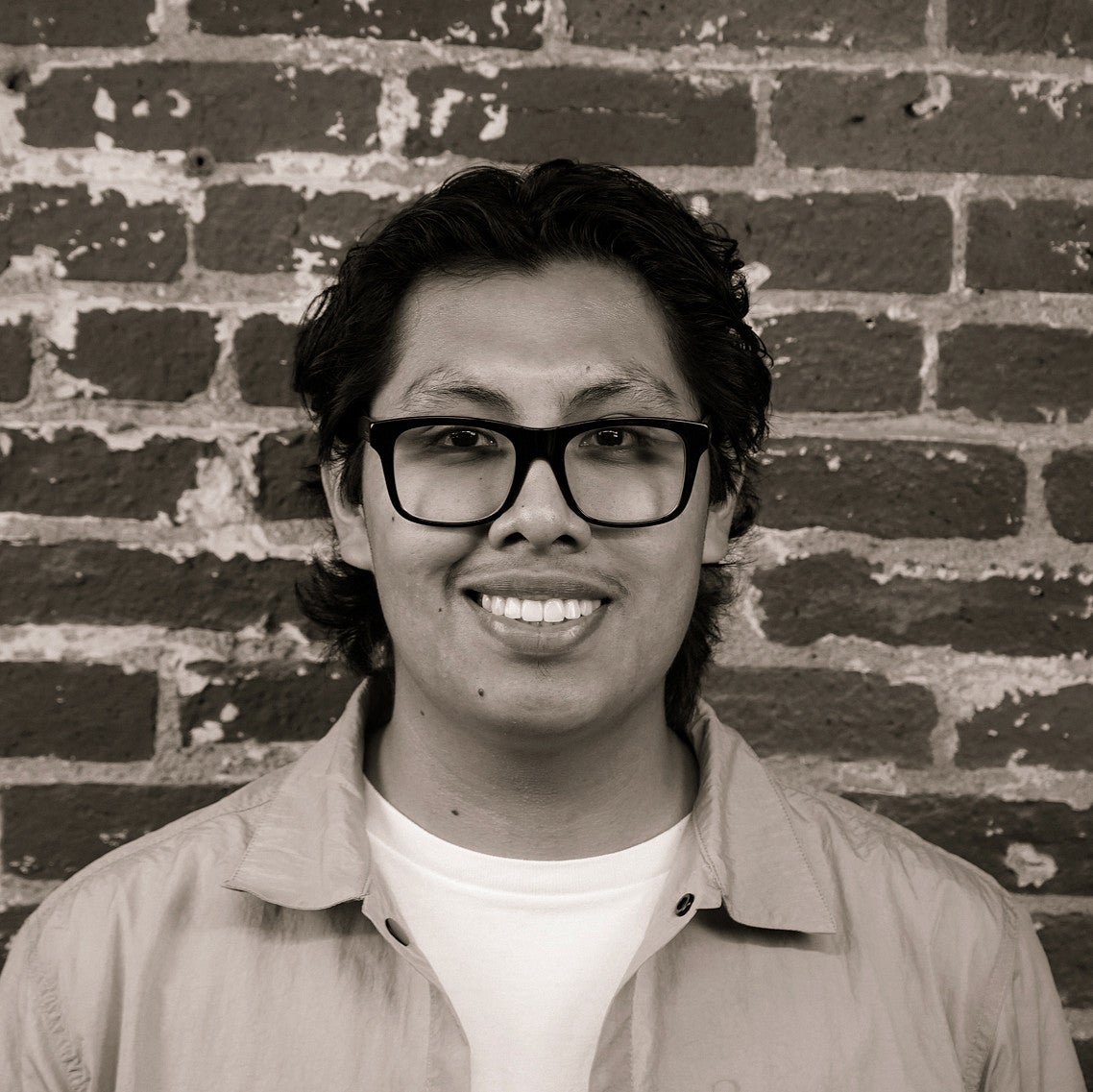 Photograph of a smiling first-year SPD student, Benjamen Lemus, in front of a brick wall.