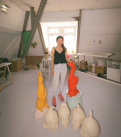 Pei-Hsuan Wang standing with a collection of her sculptures