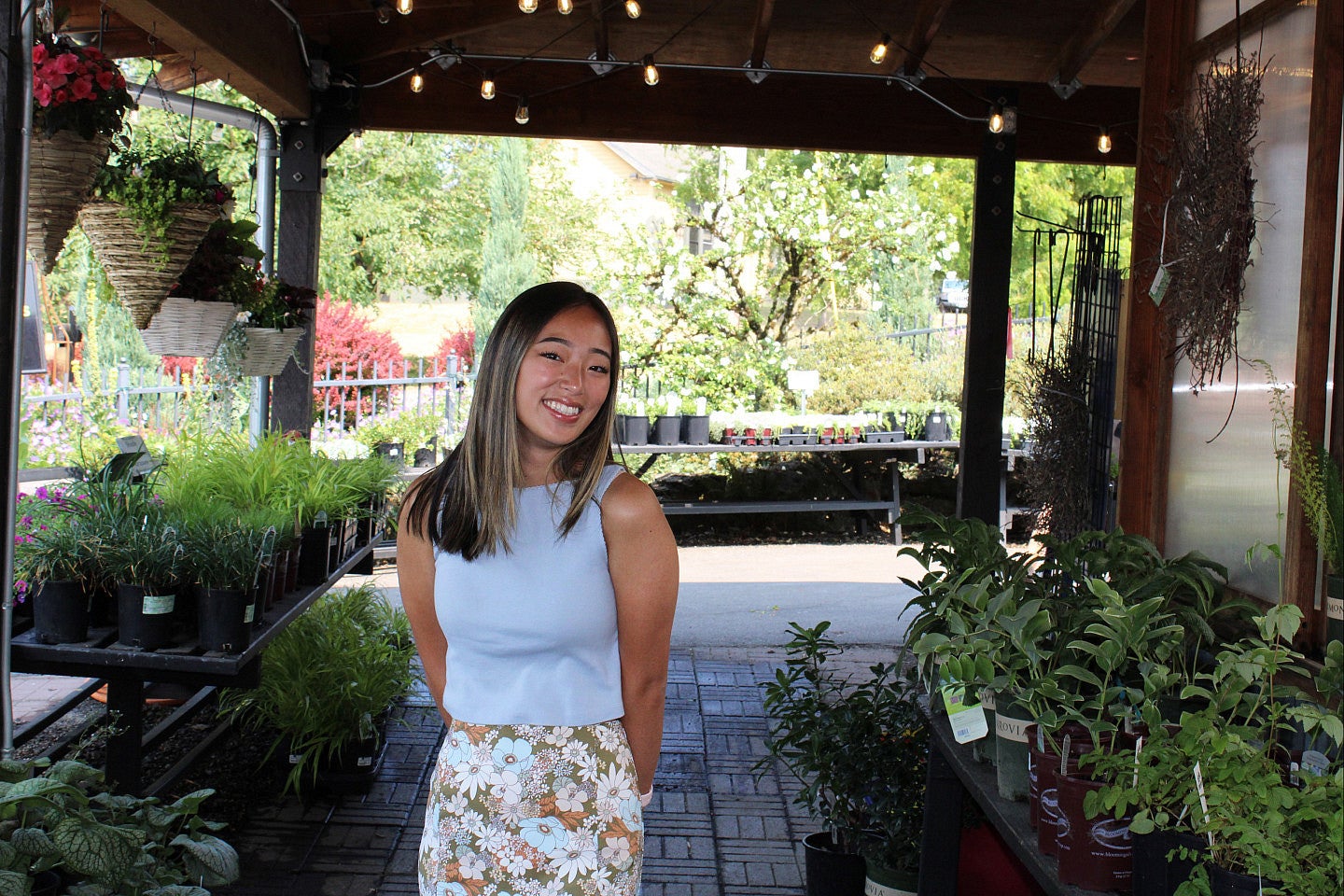 Kiera Patterson smiling on a patio surrounded by lush plants and flowers