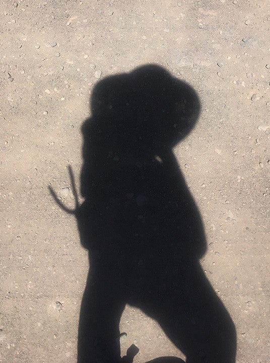 Dionne Lee headshot. Shows the shadow of Dionne Lee on a sandy ground.