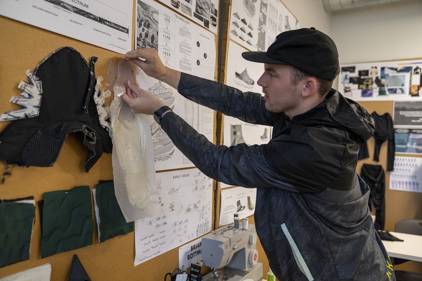 Sports Product Design student pins parts of a shoe to a board.