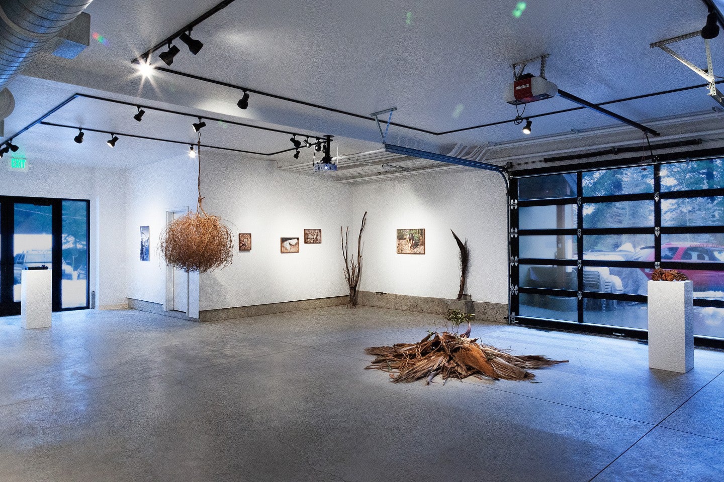 Wide angle view of a Gabie Strong exhibit. Show a myriad of different art pieces in a gallery space. 