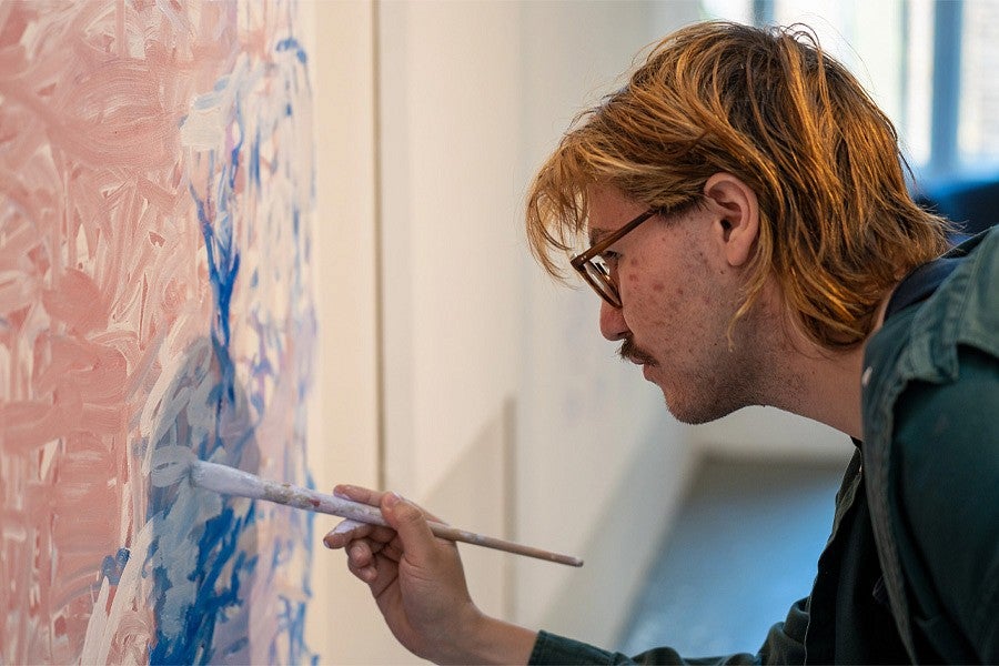 News Header for MFA Story. Shows a close up of a painter in the middle of painting. 