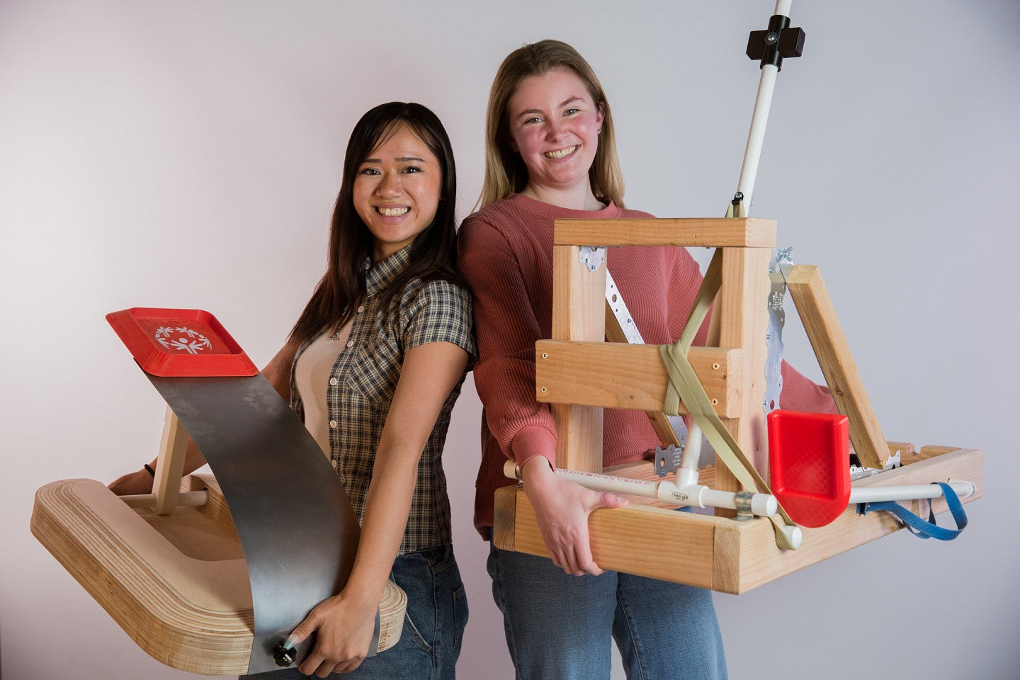 Decorative header image, shows two product design students posing with their catapults. 