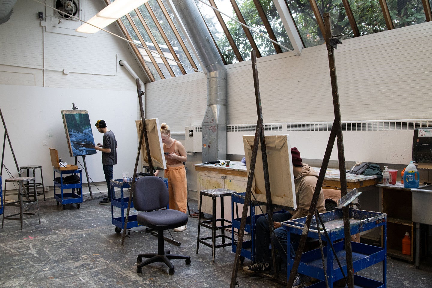 Students work on painting in a well lit, old art studio in Lawrence Hall. Decorative. 