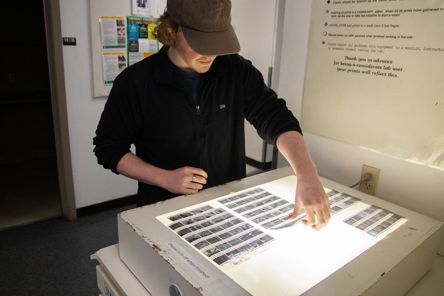 Student reviews negatives in Photography studio. Decorative. 