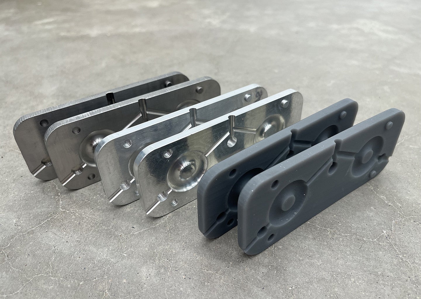 Photograph showing the testing the carbon footprint and part quality from injection molds made with SLA 3D printed acrylic resin injection molds compared to stainless steel and aluminum molds. 