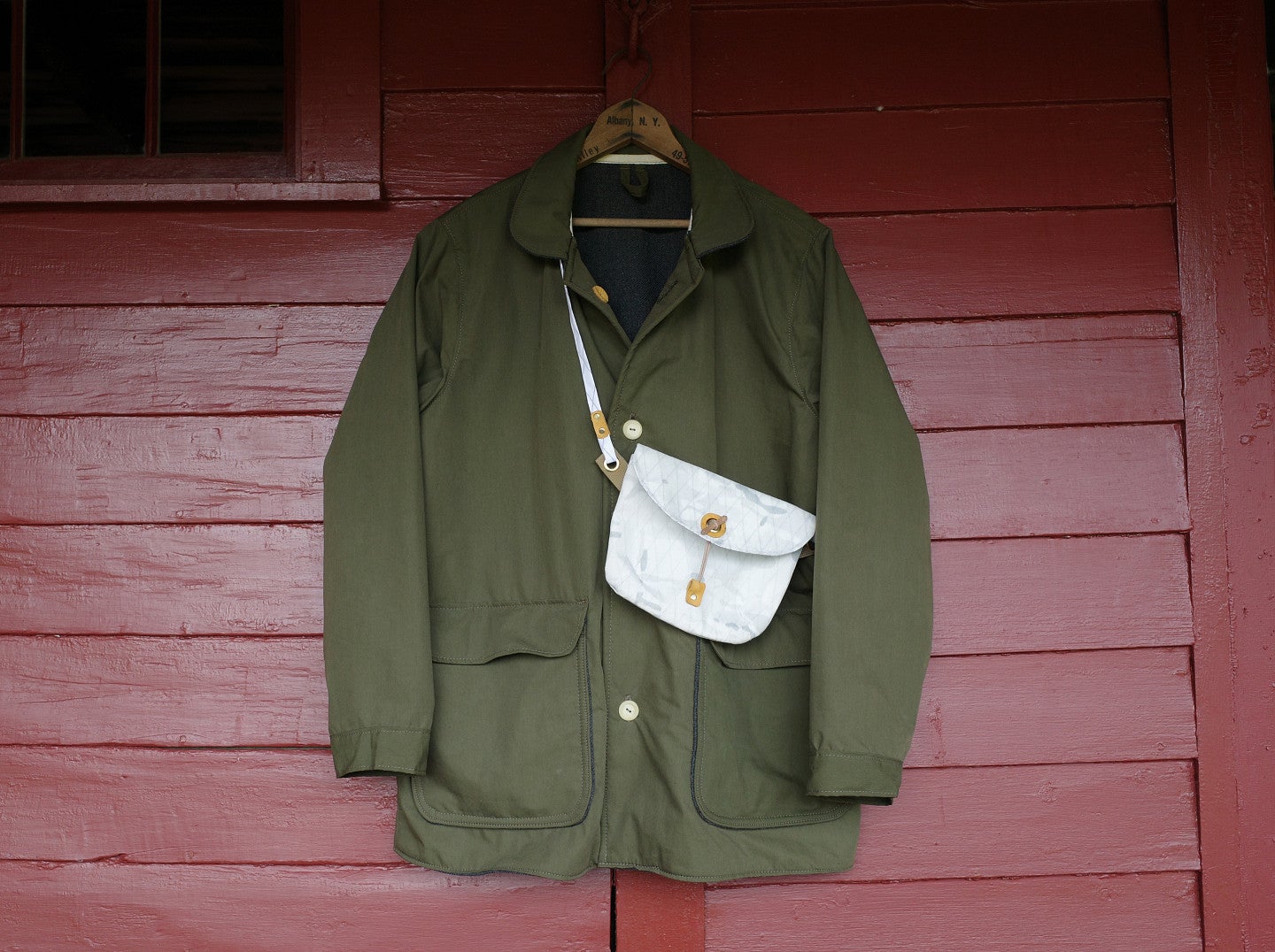 Shows a custom made green coat with a white bait bag. 