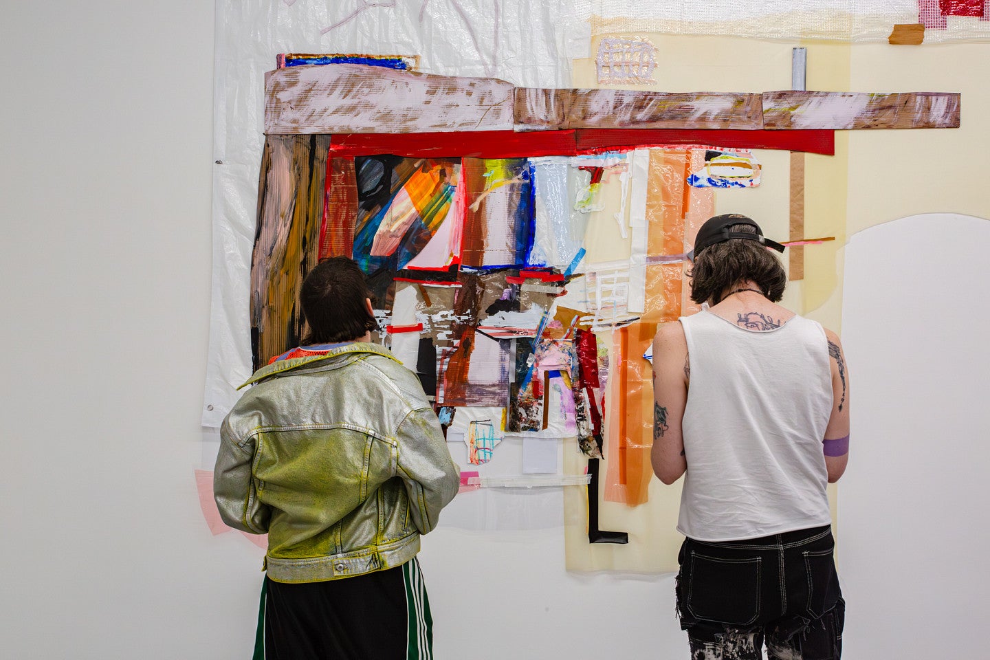 MFA exhibition with one of Elri's pieces in the middle of the frame. Shows the back of two individuals. 