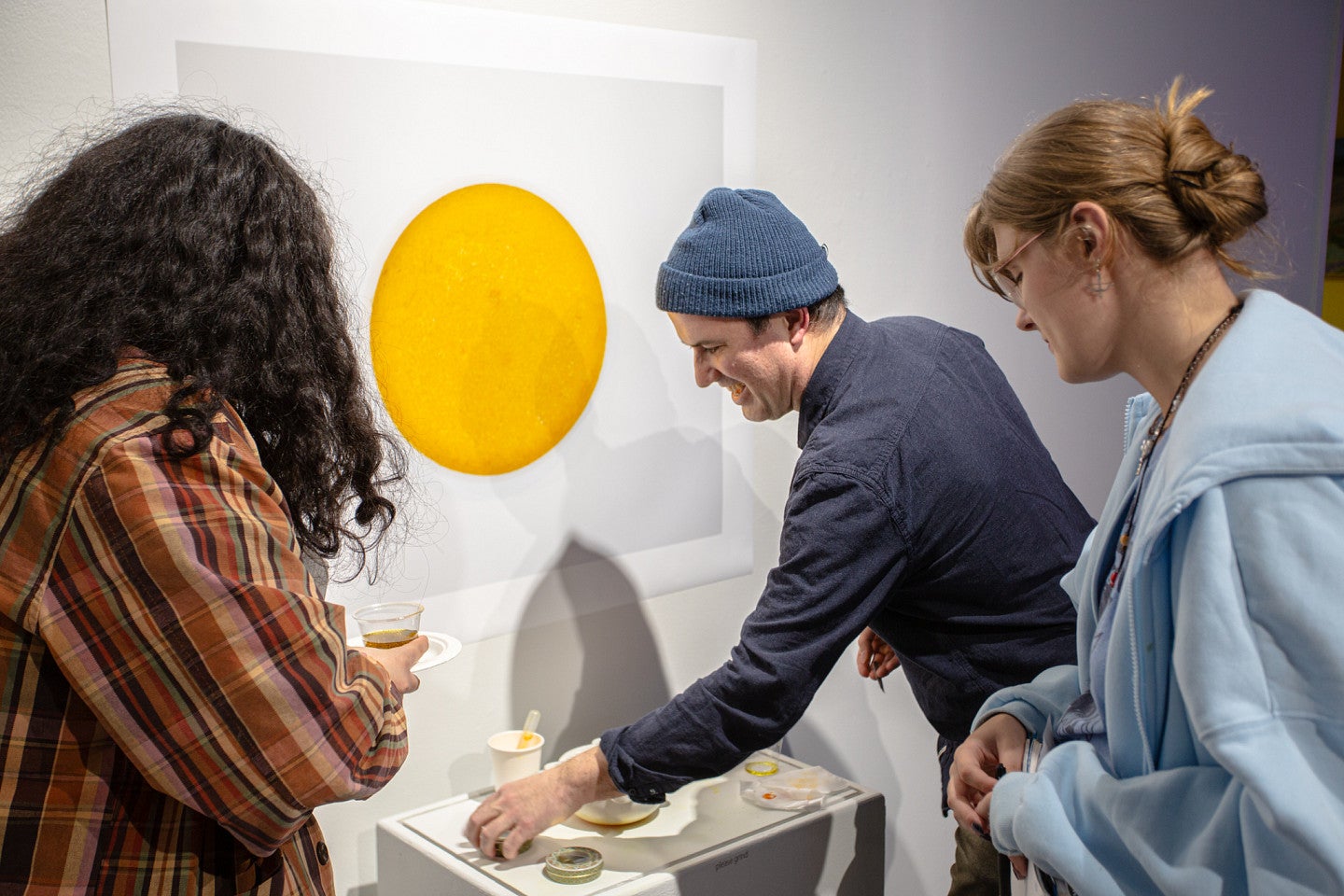 Reza Safavi refills the dish for his interactive exhibit, "Saffron", and talks with two students. 