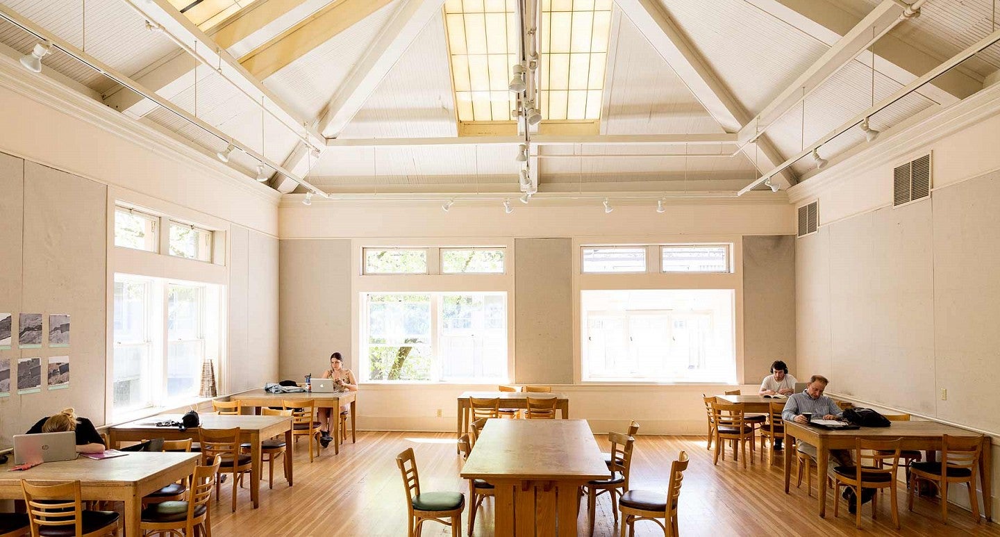 The Wilcox Hearth with vaulted ceiling, wood floor, and students studying at tables