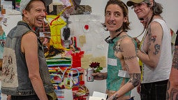 Elri looks off to the side with friends at their MFA exhibition at Ditch Projects. 