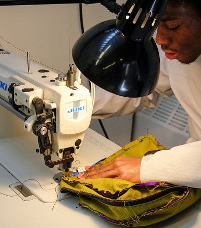 Photograph of a student sewing materials with a professional sewing machine. 