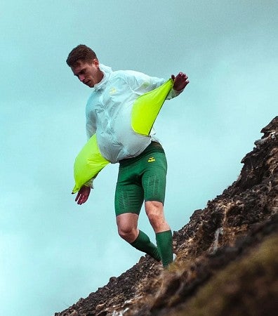 Photograph of a student stretching a jacket liner in a scenic outdoor space. 