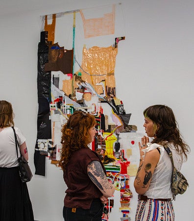 Elri's MFA exhibition with individuals in the foreground.