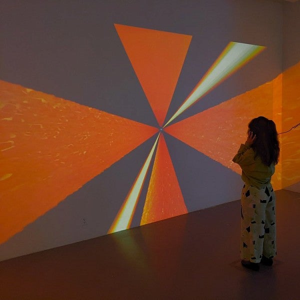 Woman standing in front of wall with orange, white, and black angular projections