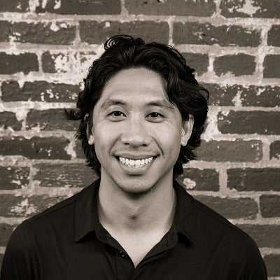 Photograph of a smiling SPD student, Aeryk Catipon, in front of a brick wall.