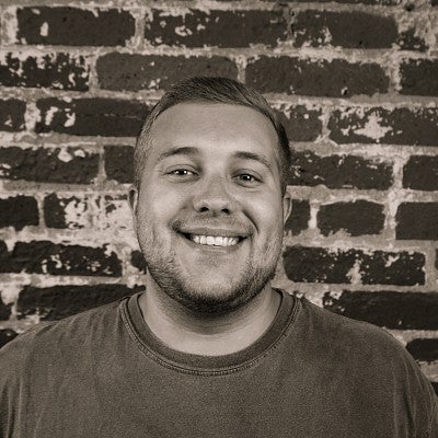 Portrait photo of smiling SPD student Sky Bunker in front of a brick wall.