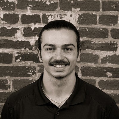 Photograph of a smiling first-year SPD student, Vic Edwards, in front of a brick wall.