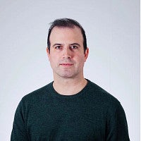 Headshot of the artist Reza Safavi. Shows a portrait of a masculine presenting person with short hair looking into the camera with a neutral face.