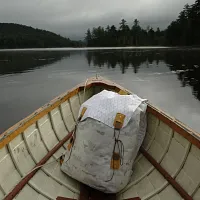 a white backpack in the front of canoe on the water